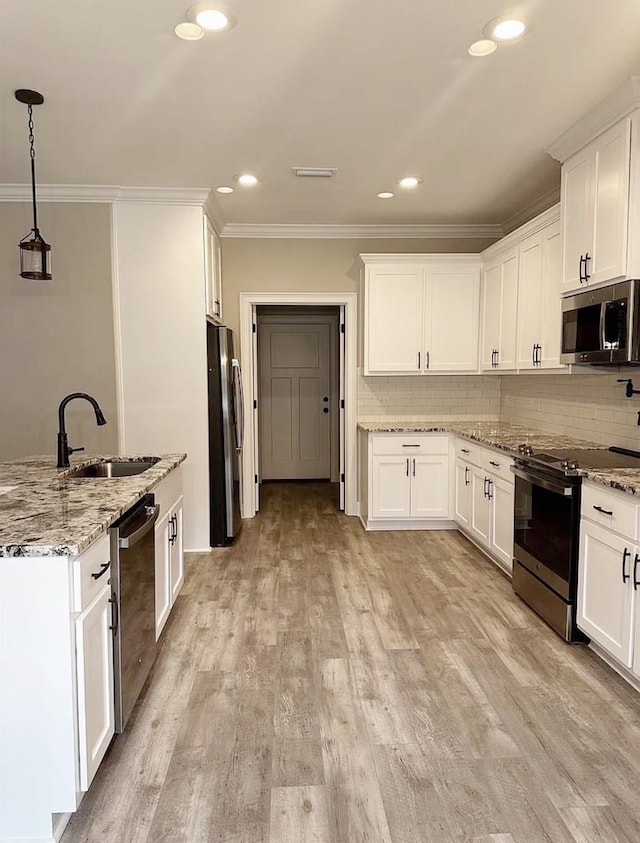 kitchen with backsplash, light wood-style flooring, appliances with stainless steel finishes, and a sink