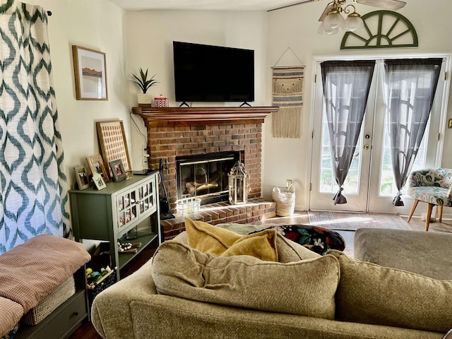 living room with a brick fireplace, french doors, and ceiling fan