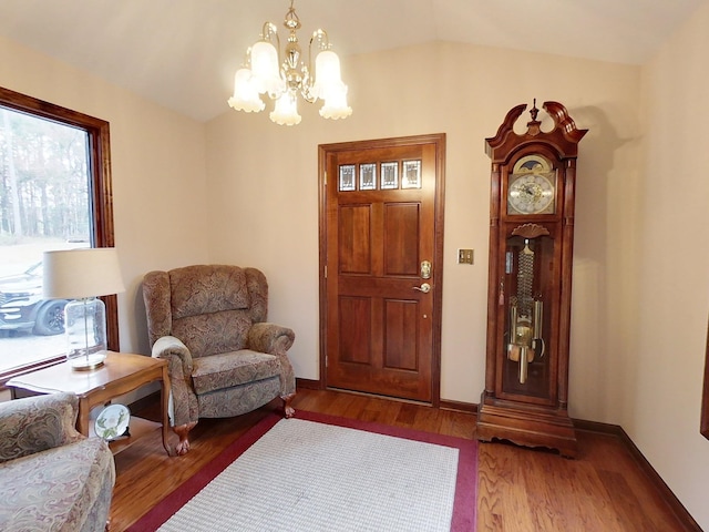 entrance foyer with hardwood / wood-style floors, lofted ceiling, and an inviting chandelier