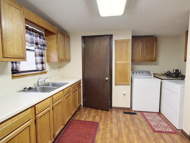 kitchen featuring washer / clothes dryer, light hardwood / wood-style floors, and sink