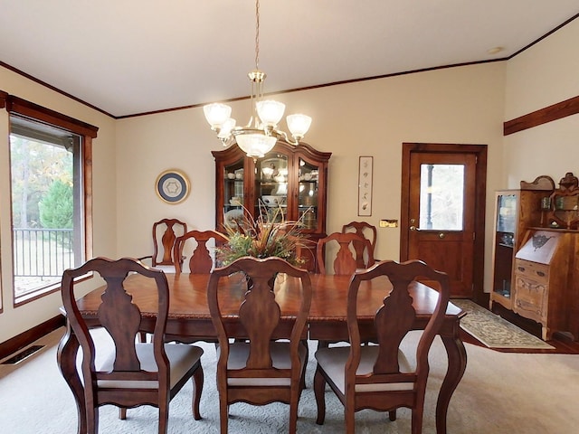 dining room featuring carpet, crown molding, and a chandelier