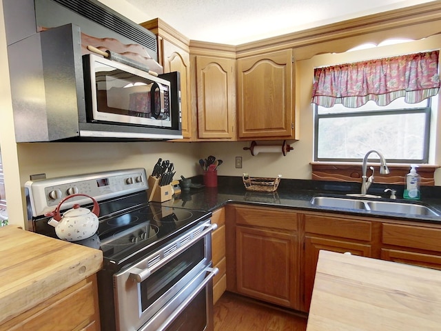 kitchen with wooden counters, sink, stainless steel appliances, and hardwood / wood-style flooring