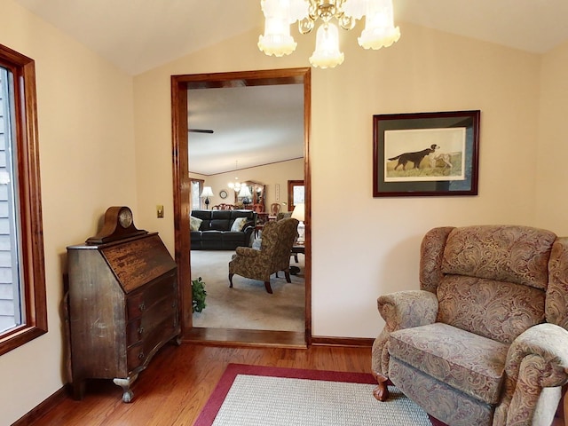 living area featuring lofted ceiling, wood-type flooring, and an inviting chandelier