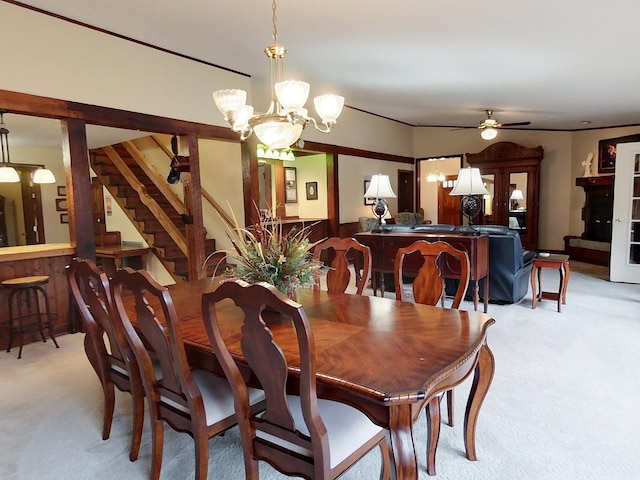 dining space featuring light carpet, wooden walls, and ceiling fan with notable chandelier