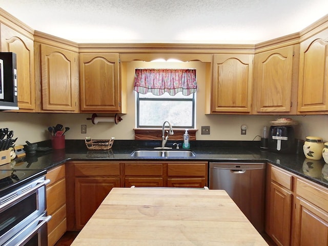 kitchen featuring sink, dark stone counters, a textured ceiling, and appliances with stainless steel finishes