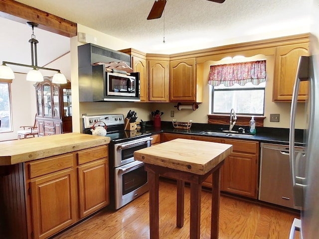 kitchen featuring ceiling fan, sink, wood counters, light hardwood / wood-style floors, and appliances with stainless steel finishes