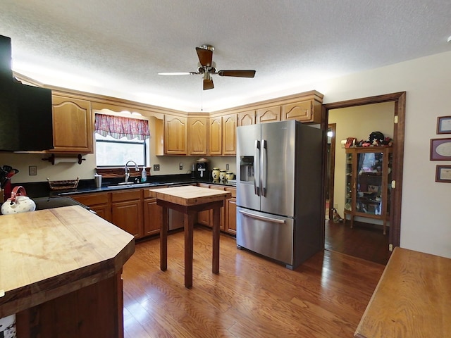 kitchen with sink, stainless steel refrigerator with ice dispenser, ceiling fan, a textured ceiling, and dark hardwood / wood-style flooring