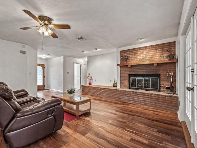 living room featuring ceiling fan, hardwood / wood-style floors, and a fireplace