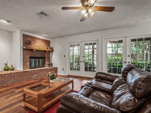 living room with french doors, ceiling fan, a fireplace, and hardwood / wood-style flooring