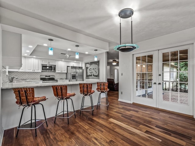 kitchen featuring white cabinets, a kitchen breakfast bar, kitchen peninsula, stainless steel appliances, and french doors