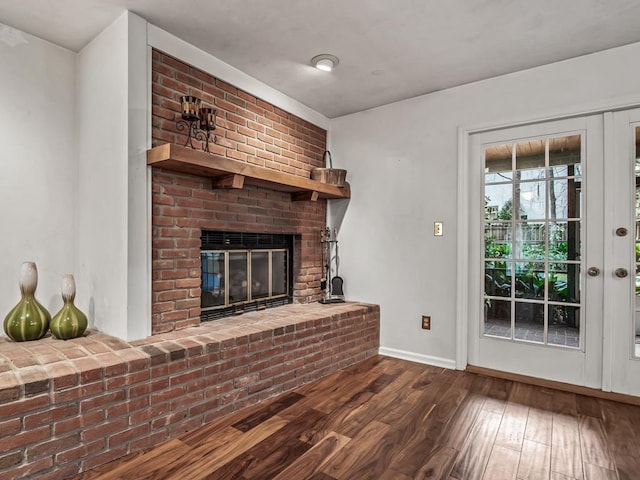 unfurnished living room featuring hardwood / wood-style flooring and a brick fireplace