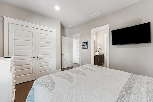 bedroom featuring connected bathroom, dark hardwood / wood-style flooring, and a closet