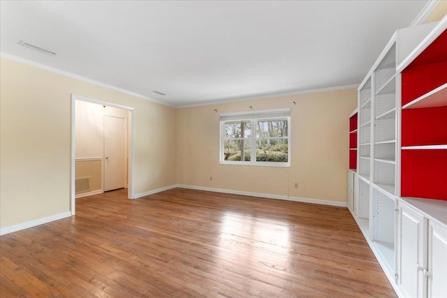 unfurnished room with crown molding, visible vents, light wood-type flooring, and baseboards