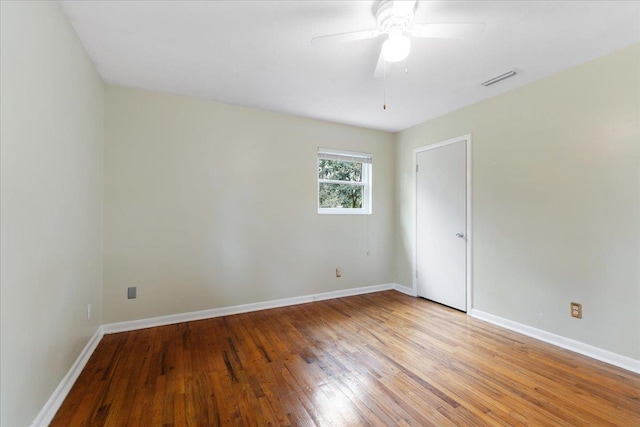 spare room with visible vents, ceiling fan, baseboards, and hardwood / wood-style flooring