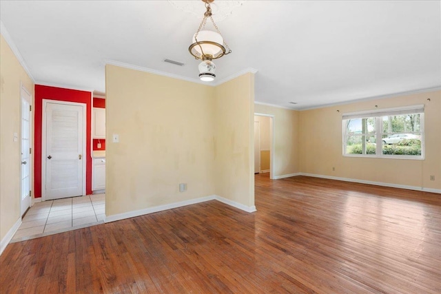 unfurnished room with light wood finished floors, crown molding, and baseboards