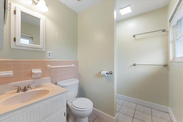 bathroom featuring tile walls, a wainscoted wall, toilet, tile patterned floors, and vanity