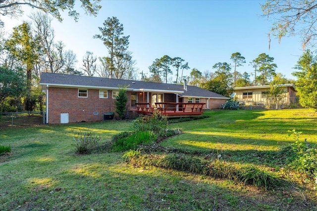 rear view of property with brick siding, fence, a yard, a deck, and crawl space