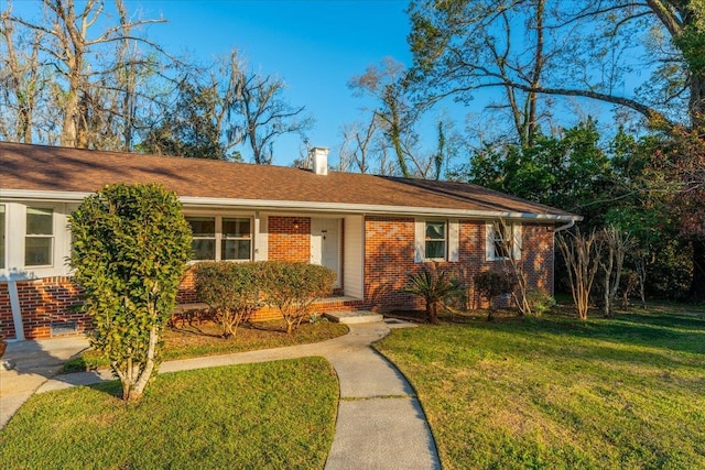 ranch-style house with a front lawn, brick siding, and a chimney