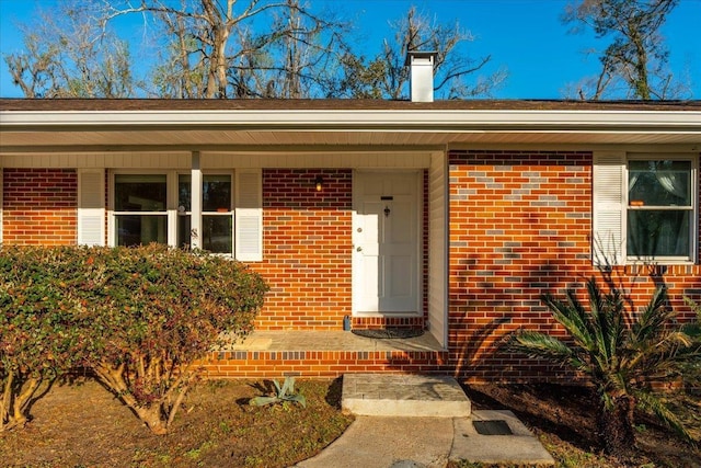 entrance to property with brick siding and a chimney