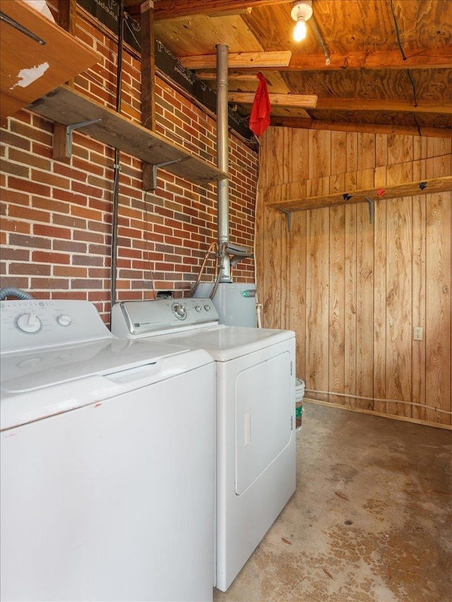 washroom featuring wooden walls, independent washer and dryer, brick wall, and laundry area