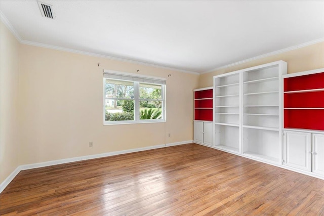 unfurnished room with visible vents, ornamental molding, baseboards, and wood finished floors