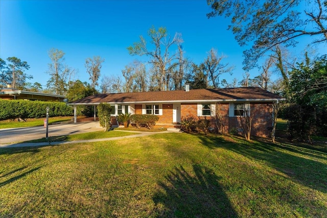 ranch-style house with a carport, concrete driveway, a front yard, brick siding, and a chimney