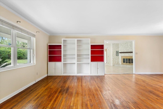 unfurnished living room featuring a fireplace, crown molding, baseboards, and wood-type flooring