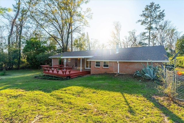 back of property featuring a yard, brick siding, and a deck