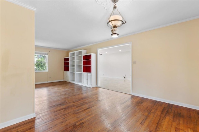 empty room featuring hardwood / wood-style floors, baseboards, and ornamental molding