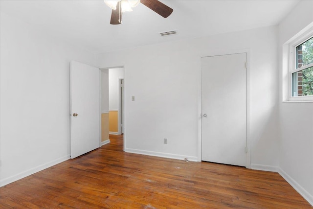 unfurnished bedroom with a ceiling fan, wood finished floors, visible vents, and baseboards