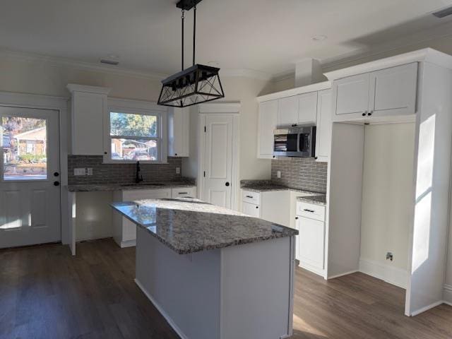 kitchen featuring white cabinetry, a center island, dark hardwood / wood-style flooring, crown molding, and decorative backsplash