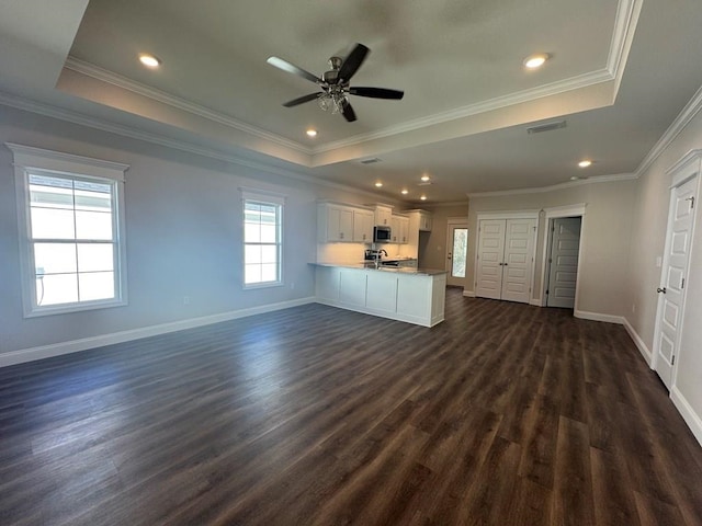 kitchen featuring white cabinets, a raised ceiling, dark hardwood / wood-style floors, ceiling fan, and kitchen peninsula