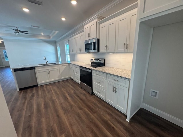 kitchen with dark wood-type flooring, white cabinets, sink, decorative backsplash, and stainless steel appliances