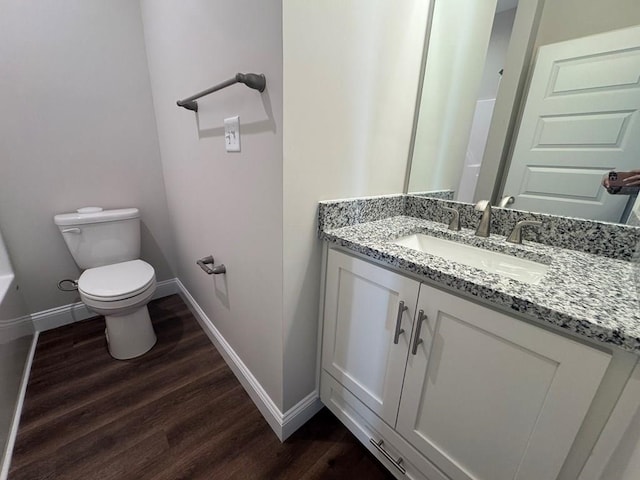 bathroom with toilet, vanity, and hardwood / wood-style flooring