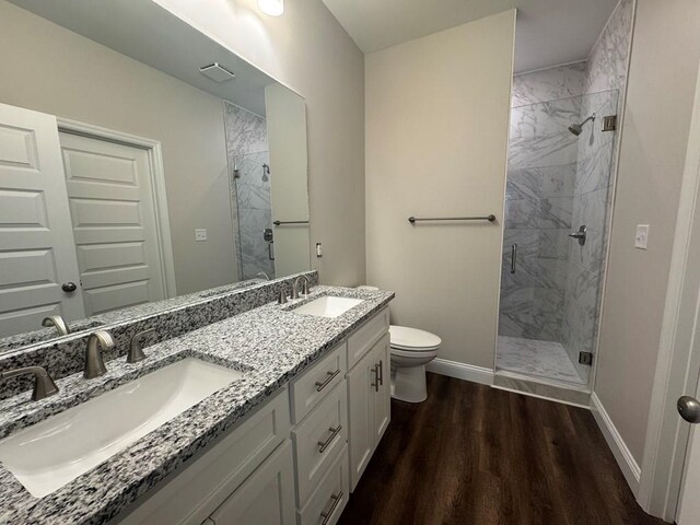 bathroom with hardwood / wood-style floors, vanity, a shower with shower door, and toilet