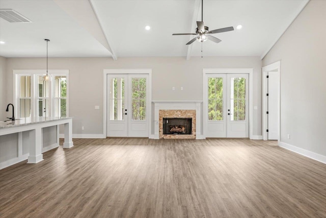 unfurnished living room featuring ceiling fan, lofted ceiling with beams, and wood-type flooring