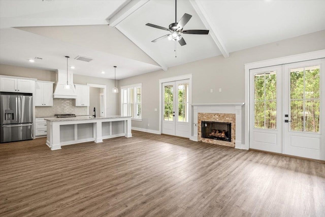 unfurnished living room featuring french doors, dark hardwood / wood-style flooring, ceiling fan, beam ceiling, and plenty of natural light