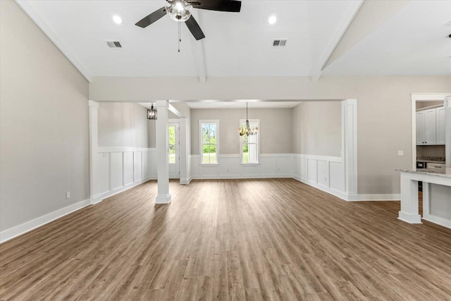 unfurnished living room featuring hardwood / wood-style floors, ceiling fan with notable chandelier, and vaulted ceiling