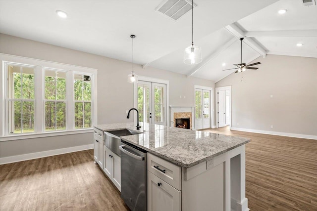 kitchen with stainless steel dishwasher, ceiling fan, sink, white cabinets, and an island with sink