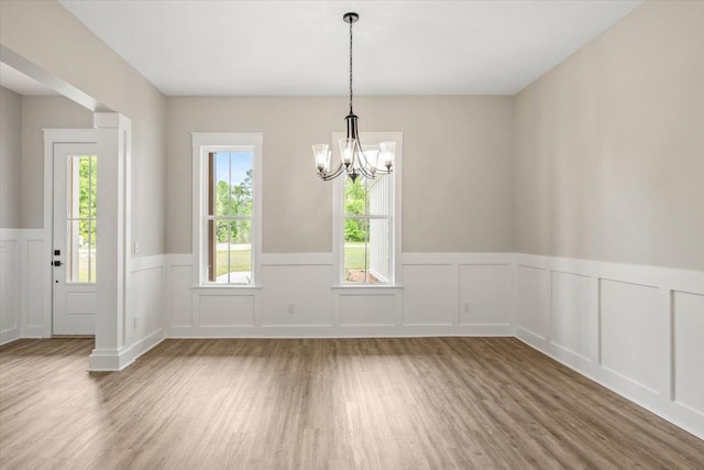 unfurnished dining area with hardwood / wood-style floors and an inviting chandelier