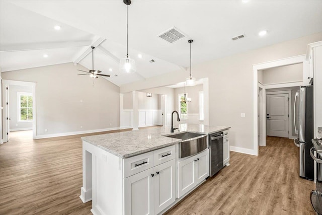 kitchen with white cabinets, sink, stainless steel appliances, and an island with sink