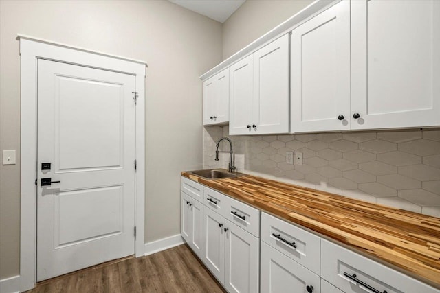 kitchen with backsplash, butcher block countertops, white cabinetry, and sink