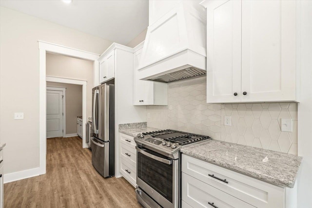 kitchen featuring custom exhaust hood, backsplash, light stone counters, white cabinetry, and stainless steel appliances