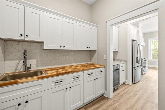 kitchen featuring white cabinetry, sink, stainless steel appliances, tasteful backsplash, and wine cooler