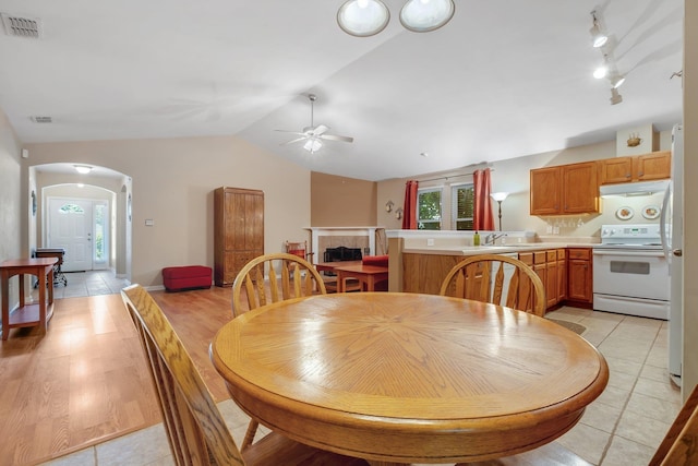5529 Green Meadows Ct, Tallahassee, FL 32303 - dining space featuring vaulted ceiling, ceiling fan, arched walkways, rail lighting, and a tiled fireplace