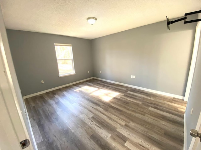 unfurnished room featuring dark wood-type flooring and a textured ceiling