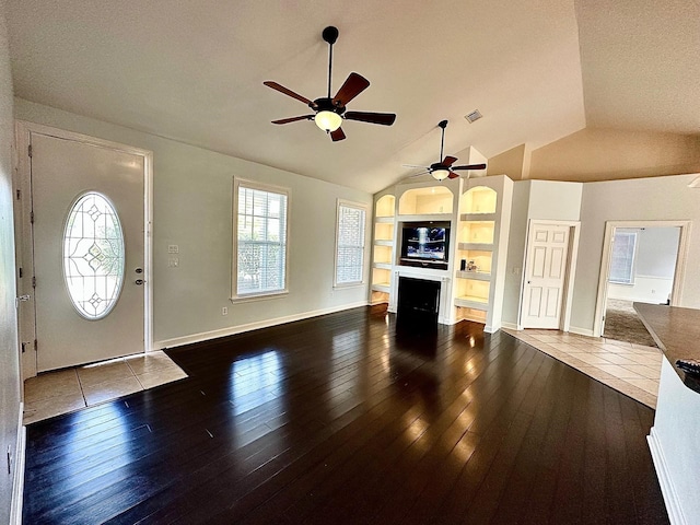 entrance foyer featuring dark wood-style floors, a fireplace, visible vents, and a wealth of natural light