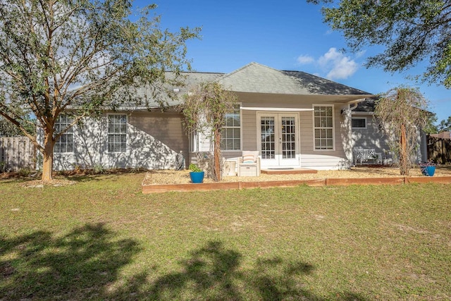 rear view of property with roof with shingles, a lawn, and french doors