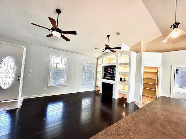 unfurnished living room featuring built in shelves, a fireplace, wood finished floors, baseboards, and vaulted ceiling