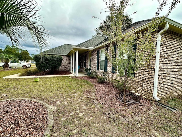 view of side of home with brick siding and a yard